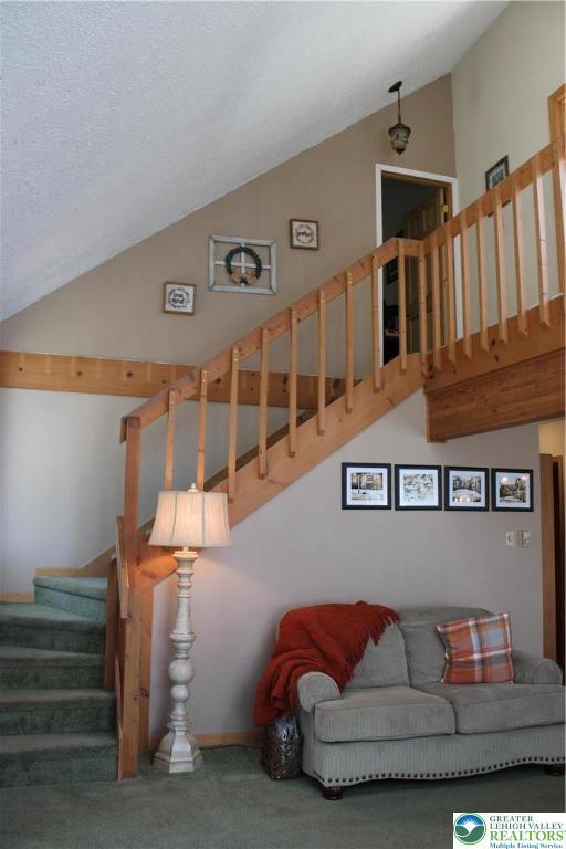 stairway featuring lofted ceiling and carpet