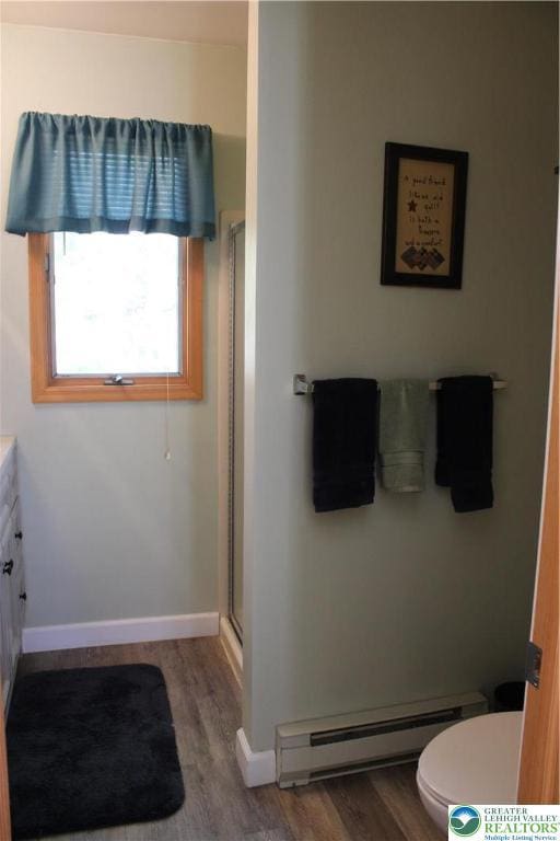 bathroom with a baseboard radiator, wood finished floors, a stall shower, and baseboards