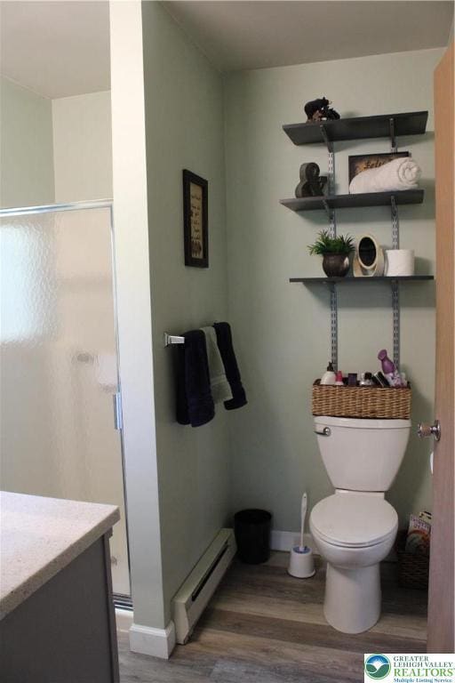full bath with baseboard heating, wood finished floors, a stall shower, and toilet