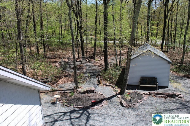 view of yard with an outdoor structure, a storage unit, and a view of trees
