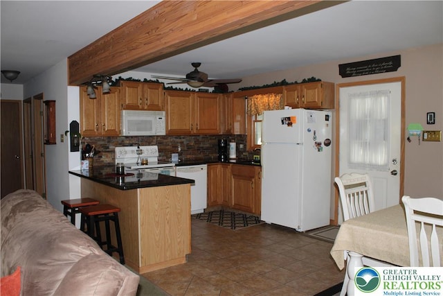 kitchen featuring white appliances, a peninsula, backsplash, dark countertops, and ceiling fan
