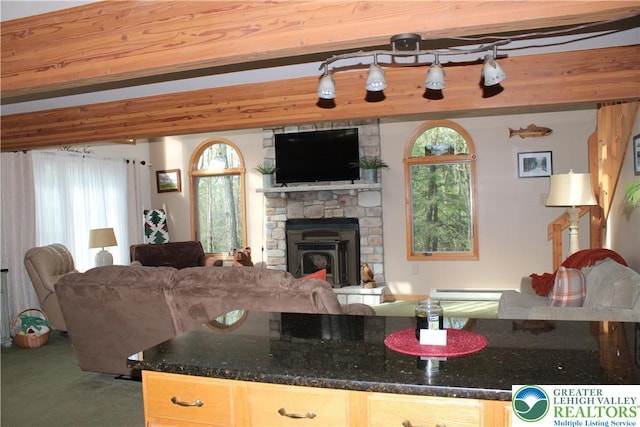 kitchen featuring open floor plan, a stone fireplace, dark stone counters, and carpet flooring