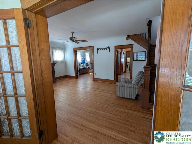 corridor with wood finished floors, baseboards, and stairway