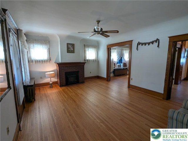 unfurnished living room with healthy amount of natural light, ceiling fan, a fireplace, and baseboards