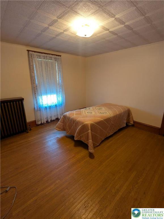 bedroom featuring radiator, wood finished floors, and baseboards