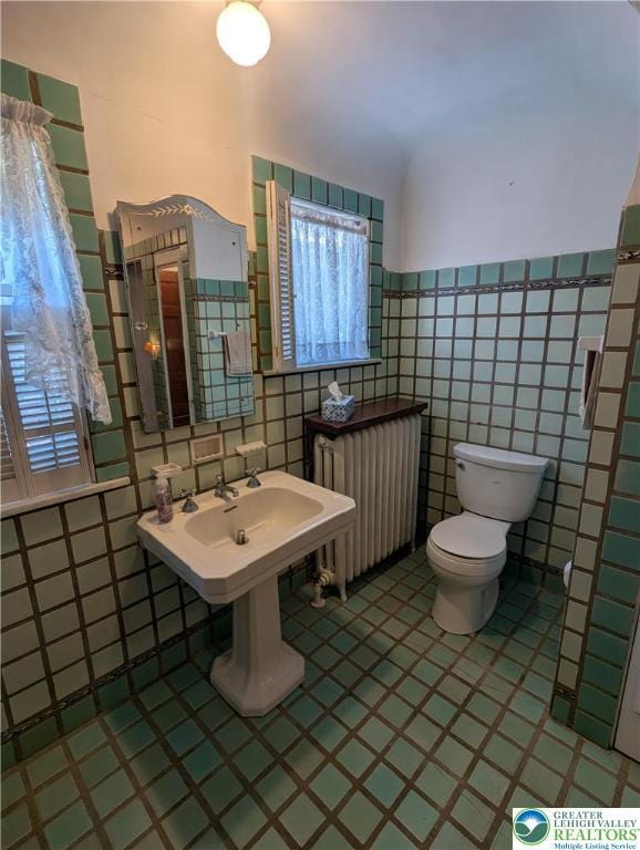 bathroom with radiator heating unit, tile walls, and toilet