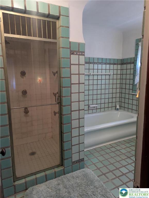 full bath featuring tile patterned floors, a shower stall, tile walls, and a bath
