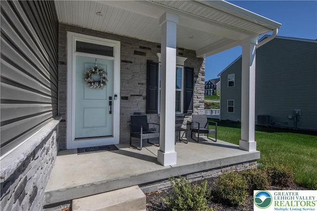 8202 Young Blvd, Upper Macungie Twp, PA 18051 - view of exterior entry with covered porch, stone siding, central AC unit, and a yard