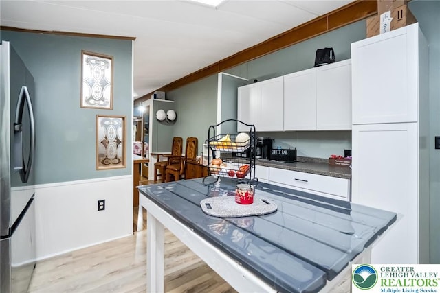 kitchen featuring stainless steel fridge with ice dispenser, light wood-style flooring, white cabinets, and dark countertops