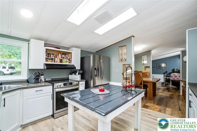 kitchen with stainless steel appliances, lofted ceiling, under cabinet range hood, dark countertops, and white cabinetry
