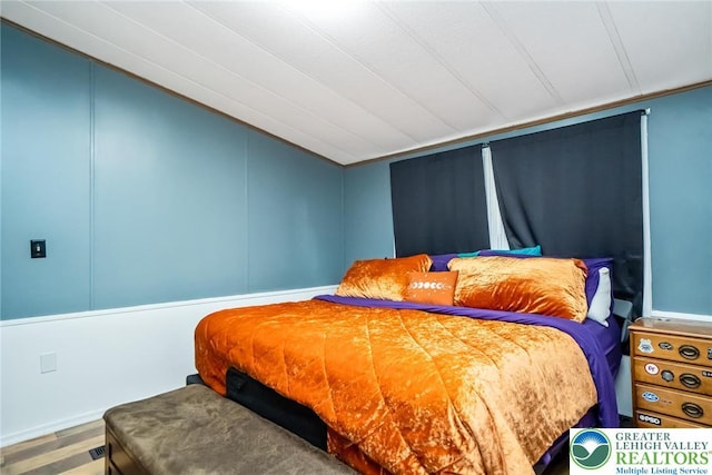 bedroom with lofted ceiling and wood finished floors