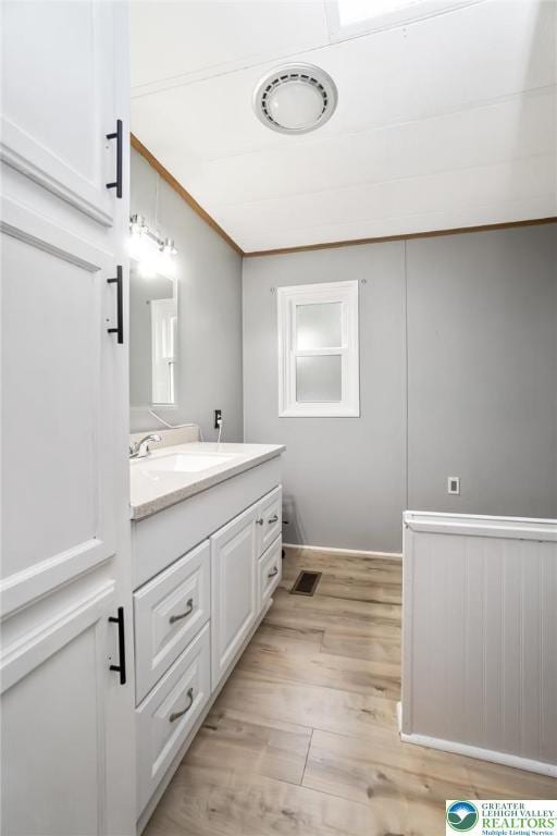 bathroom with wood finished floors, vanity, and crown molding