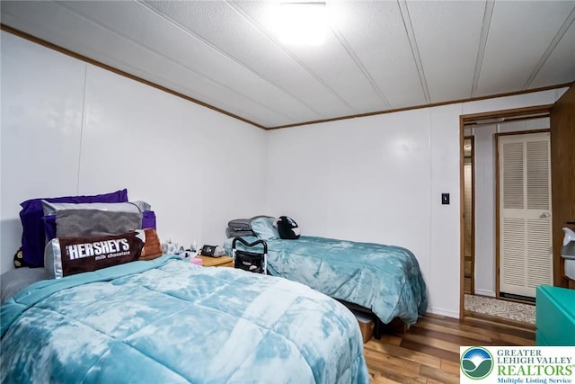 bedroom with wood finished floors, ornamental molding, and baseboards