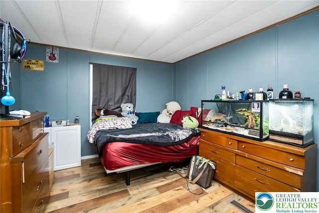 bedroom with light wood-style flooring and a decorative wall