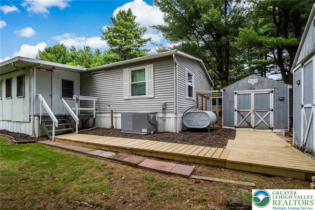 rear view of property with central AC unit, a storage shed, oil tank, and an outbuilding
