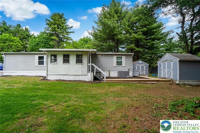 rear view of house with a shed, an outdoor structure, a yard, central AC, and entry steps