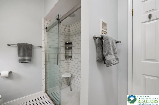 bathroom with a shower stall, toilet, and baseboards