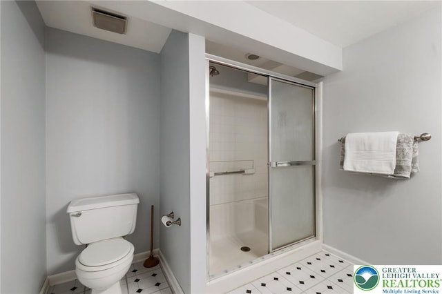 bathroom featuring a stall shower, baseboards, toilet, and tile patterned flooring