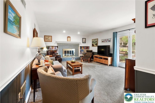 carpeted living area with wainscoting, a brick fireplace, and recessed lighting