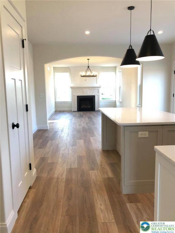 65 Island Ct, Williams Twp, PA 18042 - kitchen with light countertops, light wood finished floors, a fireplace, decorative light fixtures, and baseboards