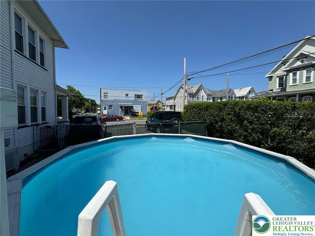 view of swimming pool featuring a fenced backyard and a residential view