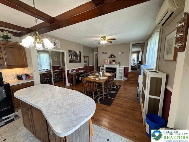 kitchen with a wall mounted AC, light countertops, electric range, a ceiling fan, and a kitchen island