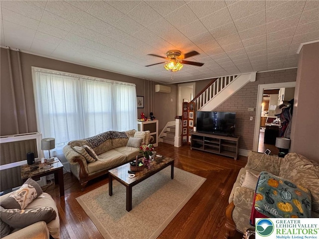 living area with stairway, a wall unit AC, wood finished floors, and ceiling fan