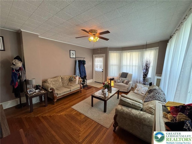 living room with a ceiling fan, crown molding, and baseboards