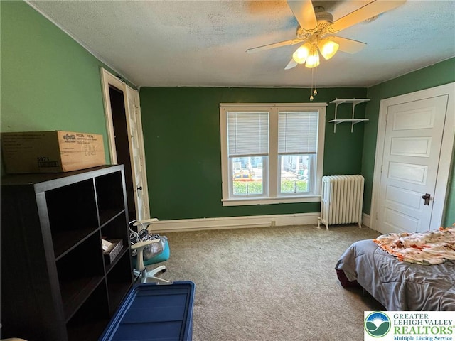 carpeted bedroom with radiator, a textured ceiling, baseboards, and ceiling fan