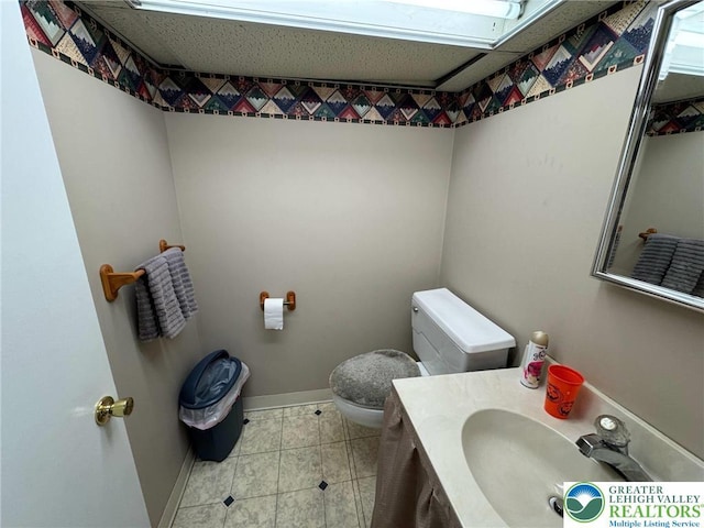 bathroom featuring tile patterned floors, baseboards, toilet, and vanity