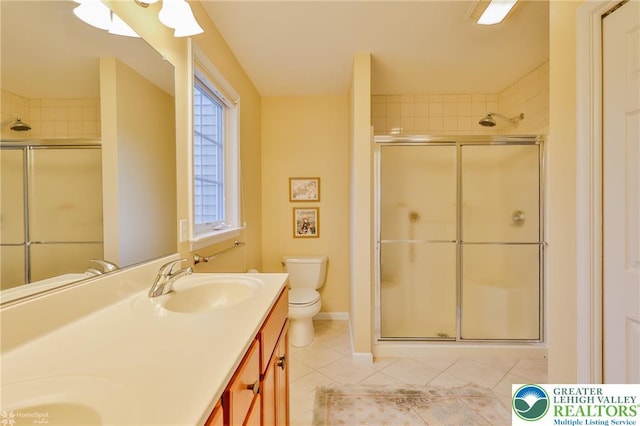 bathroom featuring tile patterned floors, a stall shower, toilet, and double vanity
