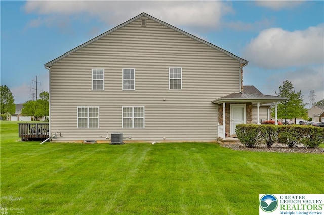 rear view of property featuring central AC and a lawn
