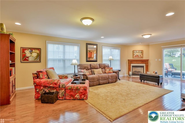 living area featuring light wood-type flooring, crown molding, a fireplace, baseboards, and recessed lighting