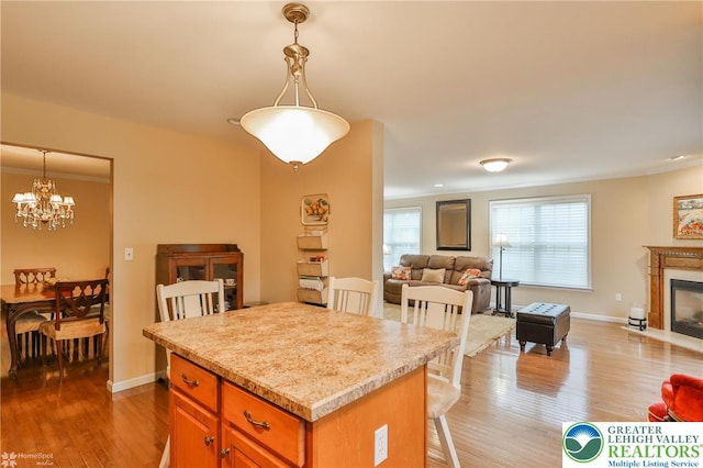 kitchen with open floor plan, light countertops, wood finished floors, a chandelier, and crown molding