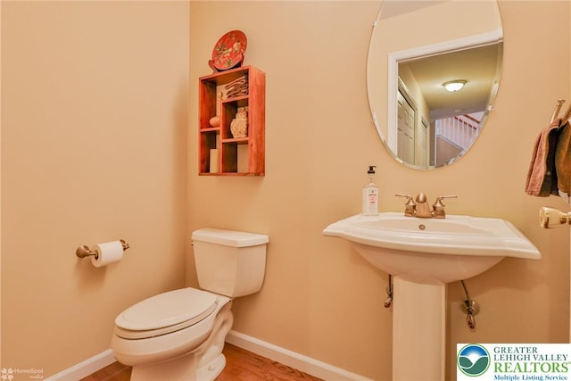 bathroom with toilet, baseboards, and wood finished floors