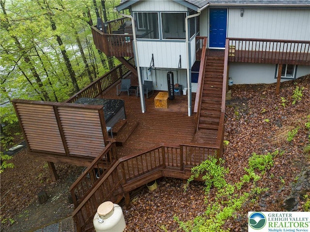 back of house with stairs, a wooden deck, a sunroom, and roof with shingles