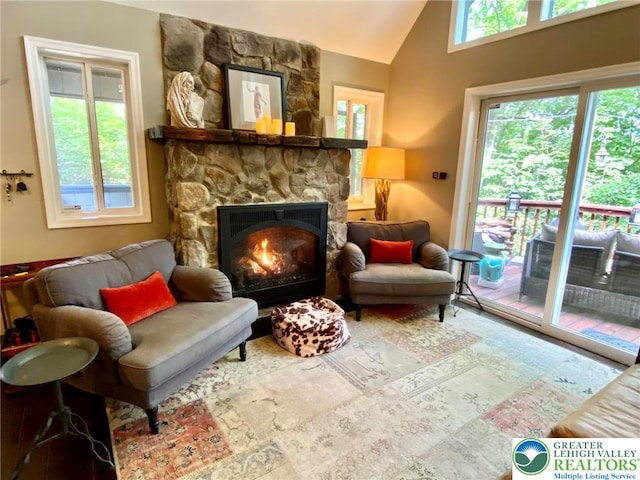 sitting room featuring a stone fireplace and vaulted ceiling