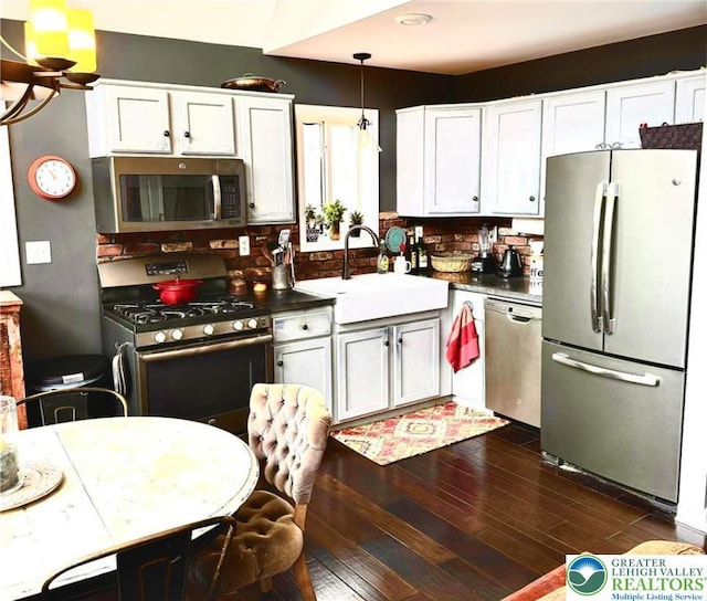 kitchen with stainless steel appliances, a sink, dark wood-style flooring, tasteful backsplash, and white cabinets