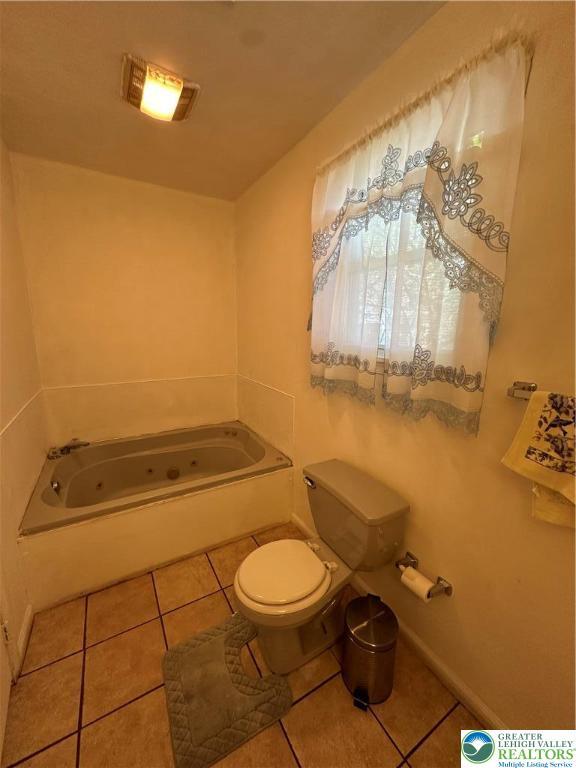 full bathroom featuring tile patterned floors, a tub with jets, and toilet