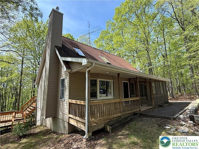 view of side of property featuring a porch and a chimney