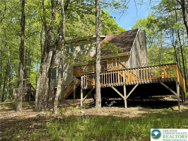 view of side of property featuring a wooden deck, stairs, and a shingled roof