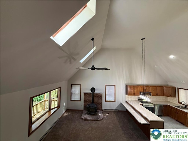 kitchen view of a sink, appliances with stainless steel finishes, light countertops, a wood stove, and brown cabinets