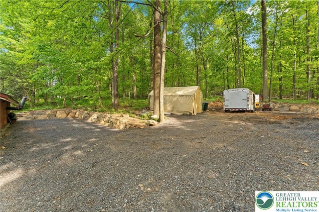 view of yard with a shed, an outbuilding, and a view of trees
