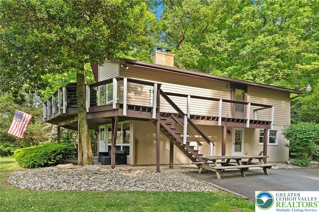back of property featuring a patio area, a chimney, a deck, and stairs