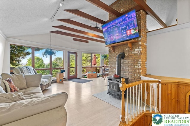 living area featuring a wood stove, healthy amount of natural light, vaulted ceiling, a textured ceiling, and wood finished floors