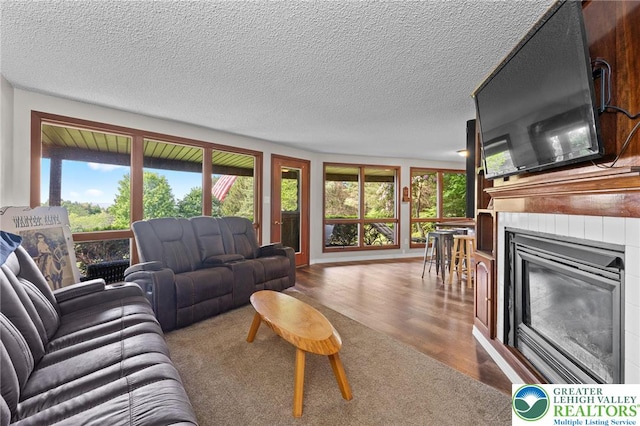 living room featuring a glass covered fireplace, wood finished floors, and a textured ceiling