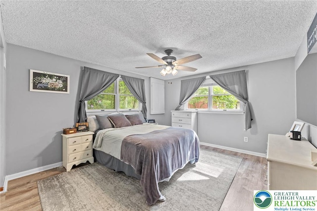 bedroom with light wood-style floors, a ceiling fan, a textured ceiling, and baseboards