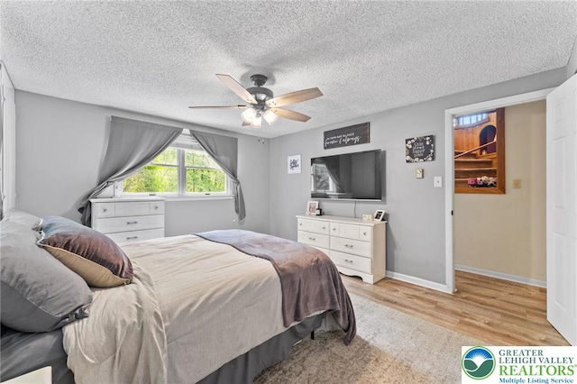 bedroom featuring light wood-style flooring, a textured ceiling, a ceiling fan, and baseboards