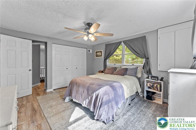 bedroom with light wood-type flooring, a textured ceiling, a ceiling fan, and a closet