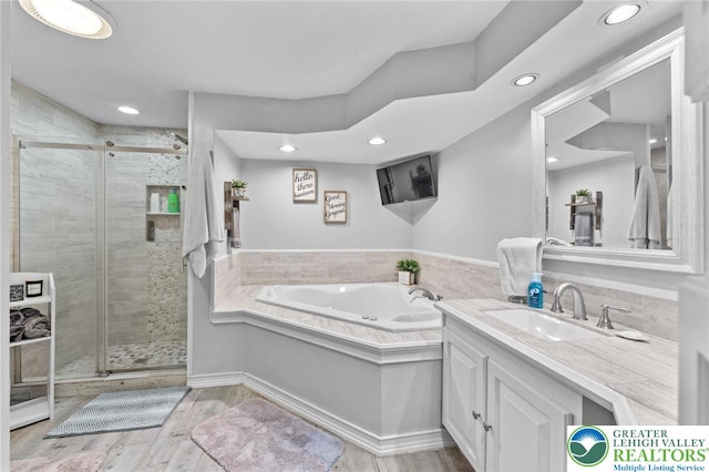 full bathroom with a shower stall, recessed lighting, a garden tub, vanity, and wood finished floors